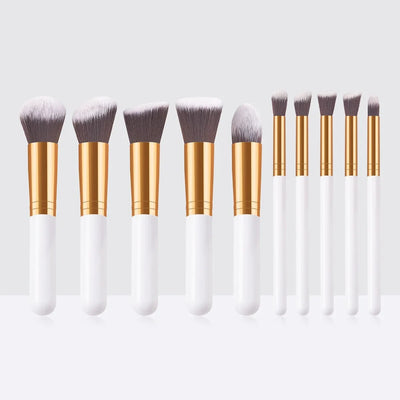 A set of 10 makeup brushes with white handles and gold ferrules, arranged in a row on a white surface.